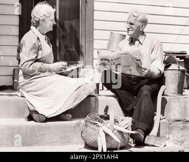 1940S SENIORIN, DIE AUF TREPPEN AN DER TÜR SASS, BOHNEN KNABBERTE, UND ZEITUNG LAS, FRISCH GEPFLÜCKTE KAROTTEN - F1499 HAR001 HARS LIFESTYLE ZUFRIEDENHEIT ÄLTERE FRAUEN VERHEIRATET LÄNDLICHER EHEPARTNER EHEMÄNNER ZU HAUSE KOPIER WELTRAUMFREUNDSCHAFT HALBLANGE DAMEN PERSONEN BAUERN MÄNNCHEN BOHNEN SENIOREN SENIOREN SENIOREN ERWACHSENE LANDWIRTSCHAFT B&W PARTNER SENIOREN FRISCH PENSIONIERT ALTER ALTER ALTER ALTER ALTER ALTER ALTER ÄUSSERE BAUERN AUS DEM UNTEREN WINKEL, SIE BERUFE WÄHLTE ÄLTERE VERBINDUNG KONZEPTIONELLE MÖHREN ÄLTERER MANN ER SCHNAPPT ZUSAMMENARBEIT ÄLTERE FRAUEN ENTSPANNUNGS-EHEFRAUEN SCHWARZ AUF WEISS Stockfoto