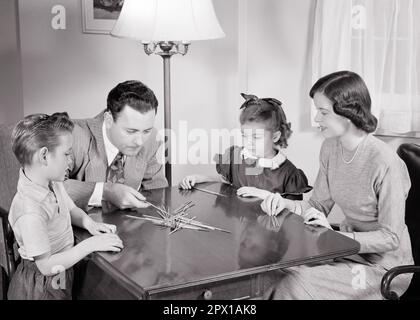 1940S 1950S FAMILIENVATER, MUTTER, SOHN UND TOCHTER SITZEN ZUSAMMEN AM TISCH UND SPIELEN RETRO-SALON-SPIEL MIT HÖLZERNEN PICK-UP-STICKS - J2462 HAR001 HARS NOSTALGISCHES PAAR 4 MÜTTER ALTE ZEIT NOSTALGIE BRUDER ALTE MODE SCHWESTER 1 JUGENDWETTKAMPF SÖHNE FAMILIEN LEBENSSTIL MENTALE FRAUEN VERHEIRATETE BRÜDER EHEPARTNER EHEMÄNNER ZUHAUSE KOPIERRAUM HALBE LÄNGE DAMEN TÖCHTER MENSCHEN FÜRSORGLICHE MÄNNER GESCHWISTER SCHWESTERN VÄTER B&W-PARTNER ZIELT AUF FERTIGKEITEN, KÖRPERLICHE AKTIVITÄT, HOCHWINKEL FREIZEITHANDBUCH UND VÄTER GESCHWISTERVERBINDUNG STÄBCHEN STILVOLLE UNTERSTÜTZUNG ABHOLUNG FAMILIENSPASS FÜR JUGENDLICHE IM MITTLEREN ERWACHSENENALTER Stockfoto