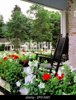 1990S TOPFGERANIEN UND WEISSE PETUNIEN AUF FRIEDLICHER VERANDA MIT SCHWARZEN SCHAUKELSTÜHLEN SOMMER IN GRAFTON VERMONT USA - KB28279 SEB001 HARS TOPFAUSFLUG UND KURZURLAUB GERANIEN FERIENHÄUSER FRIEDLICHE PETUNIEN KONZEPTIONELLE RESIDENZ GRAFTON SOLITUDE VT NEW ENGLAND ENTSPANNUNGSZEIT URLAUB ALTMODISCH Stockfoto
