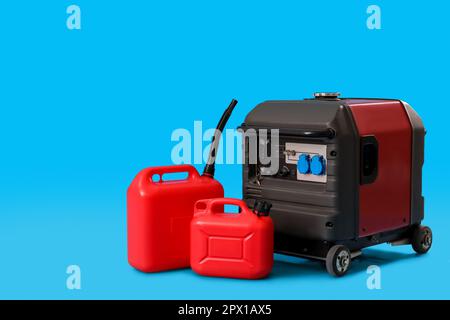 Tragbarer Benzingenerator mit Kanistern auf blauem Hintergrund Stockfoto