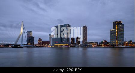 Panoramablick auf den Hafen von Rotterdam mit der Erasmus-Brücke und den hohen Gebäuden, die ihn umgeben, in der Dämmerung Stockfoto