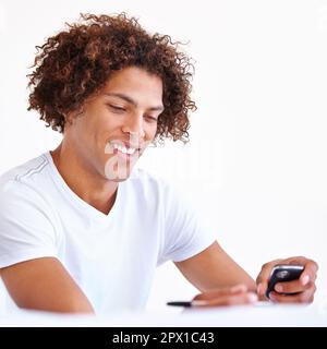 Durch SMS in Kontakt bleiben. Nahaufnahme eines gutaussehenden ethnischen Mannes mit Telefon und Stift. Stockfoto