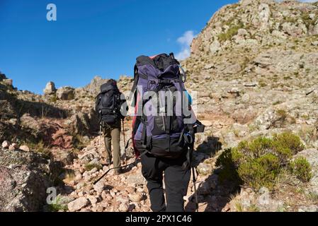 Nicht erkennbare Bergsteiger, die einen Wanderweg inmitten einer felsigen Berglandschaft in Los Gigantes, Cordoba, Argentinien, aufsteigen, ein ideales Touristenziel. Stockfoto