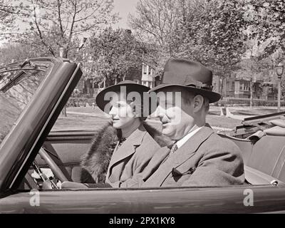 1930S LÄCHELNDES PAAR, MANN UND FRAU, DIE ZUSAMMEN AUF DEM VORDERSITZ DES CABRIOLETS ROADSTER AUTO FAHREN - M5470 HAR001 HARS GESICHTSBEHANDLUNG FAHRZEUGSICHERHEIT ZUFRIEDEN FREUDE LEBENSSTIL ZUFRIEDENHEIT WEIBLICHE VERHEIRATETE EHEPARTNER EHEMÄNNER LUXUS KOPIERRAUM DAMEN PERSONEN AUTO MÄNNER SELBSTVERTRAUEN TRANSPORT AUSDRÜCKE B&W PARTNER FREEDOM ANZUG UND KRAWATTE HAPPY HEAD AND SHOULDERS FRÖHLICH UND AUTO RECREATION ROADSTER STOLZ LÄCHELT SUNDAY DRIVE KONZEPT AUTOS FRÖHLICHE, STILVOLLE FAHRZEUGE MITTELGROSSER ERWACHSENER MANN MITTELGROSSER ERWACHSENER FRAU ENTSPANNUNG ZUSAMMENSEIN FRAUEN SCHWARZ-WEISS WEISSE ETHNISCHE ZUGEHÖRIGKEIT HAR001 ALTMODISCH Stockfoto