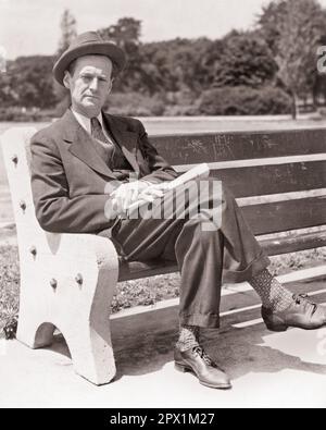 1930S 1940S REIFER MANN, DER AUF DER PARKBANK SITZT UND EINE ZEITUNG IN EINEM BUSINESS-ANZUG HÄLT UND AUF DIE KAMERA SCHAUT. S1897 HAR001 HARS DURCHGEHENDE PENSIVE PERSONEN AUFMERKSAM MÄNNER RISIKO WESTE AUSDRÜCKE B&W RUHE TRAURIGKEIT AUGENKONTAKT ANZUG UND KRAWATTE TRÄUME REFLEKTIERENDES DENKEN STOLZ REFLEKTIERT DENKEN DENKEN DENKEN IM GEDANKLICHEN DREITEILIGEN ANZUG VERLORENGEGANGEN DENKEN AUFRICHTIG ENTMUTIGT FEIERLICH KONZENTRIERT INTENSIV MITTELERWACHSENER, MITTELERWACHSENER MANN LÖSUNGEN SCHWARZ-WEISS VORSICHTIG KAUKASISCHE ETHNISCHE ZUGEHÖRIGKEIT UNTER BERÜCKSICHTIGUNG VON DOUR DOWNCAST ERNSTHAFT HAR001 INTENT ALTMODISCH AUS ARBEITSLOS Stockfoto