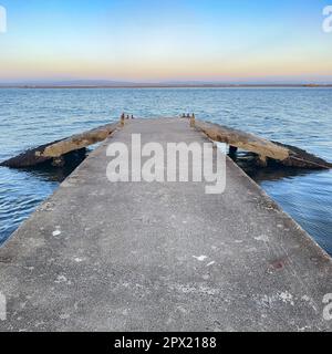 Leerer Betonpier zur Ria de Aveiro in Portugal mit dramatischem Himmel und ruhigem Wasser. Stockfoto