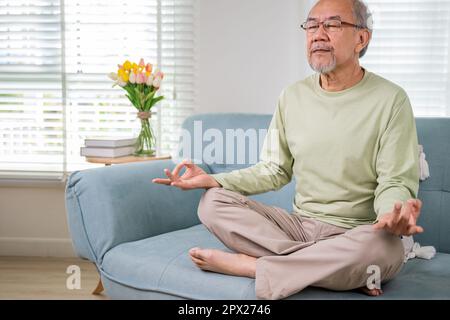 Asiatischer alter Mann praktiziert Yoga und Meditation in Lotusposition und geschlossenen Augen, Lebensstil älterer Mann Lotusposition macht Yoga für das mentale Gleichgewicht Atmung Stockfoto