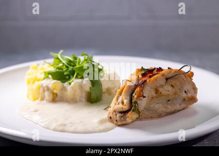 truthahnbrötchen gefüllt mit Spinat und Schinken serviert mit Kartoffelpüree und Sahne Sauce Stockfoto