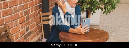 Glückliche muslimische Frau mit Videoanruf auf dem Smartphone in der Stadt. Stockfoto