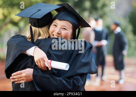 Wir haben endlich unseren Abschluss gemacht. Zwei College-Absolventen umarmen sich in Herzlichen Glückwunsch. Stockfoto