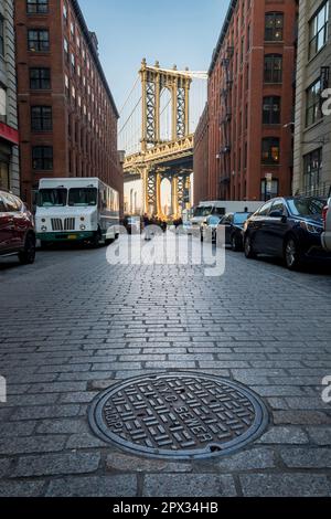 Manhattan, New York, USA - Dezember 11. 2018: Brooklyn Bridge aus der D.U.M.B.O. Gegend gesehen, wobei mehrere Autos auf jeder Seite der Straße geparkt sind Stockfoto