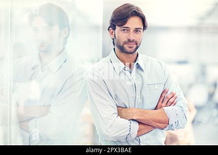 HES ein selbstbewusster junger Geschäftsmann. Porträt eines hübschen jungen Geschäftsmannes, der in seinem Büro steht. Stockfoto