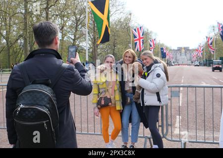 London, Großbritannien. Touristen machen ein Foto in der Mall, die mit Union Jacks und den Commonwealth-Flaggen vor der Krönung des Königs dekoriert ist. Stockfoto