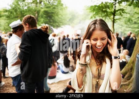 Im Bühnenbereich. Eine junge Frau, die auf einem Outdoor-Festival mit ihrem Smartphone zu kämpfen hat. Stockfoto