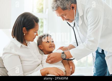 Folge der Stimme deines Herzens. Ein reifer Arzt, der den Herzschlag eines kleinen Jungen während einer Untersuchung zuhause hört Stockfoto