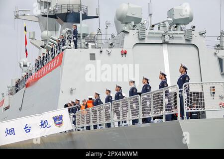 YANTAI, CHINA - 25. APRIL 2023 - Offiziere und Matrosen des chinesischen Marineschiffs Yantai stehen an der Seite des Schiffs in Yantai, Ostchina Shandong PR Stockfoto