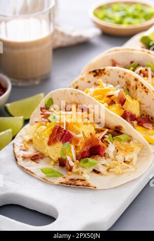 Frühstückstacos mit Kartoffelrösti, Rührei, Käse und Speck Stockfoto