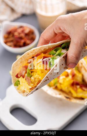 Frühstückstacos mit Kartoffelrösti, Rührei, Käse und Speck Stockfoto