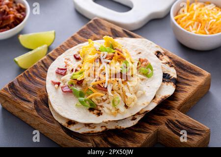 Frühstückstacos mit Kartoffelrösti, Rührei, Käse und Speck Stockfoto