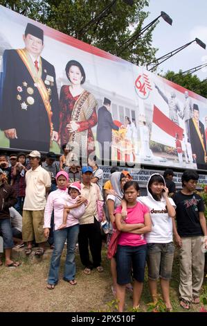Menschen vor einem Plakat zum Gedenken an 64 Jahre Unabhängigkeit mit Bildern des indonesischen Präsidenten (Susilo Bambang Yudhoyono (SBY)) und Vizepräsidenten Stockfoto