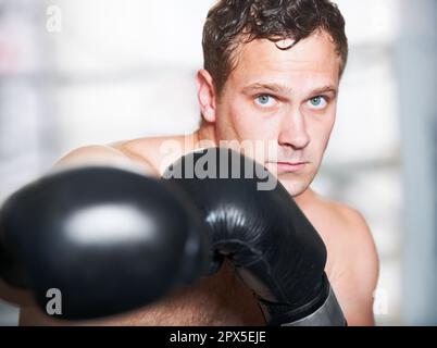 Professioneller Boxer. Ein junger, gutaussehender Boxer, der einen Schlag in die Kamera wirft. Stockfoto