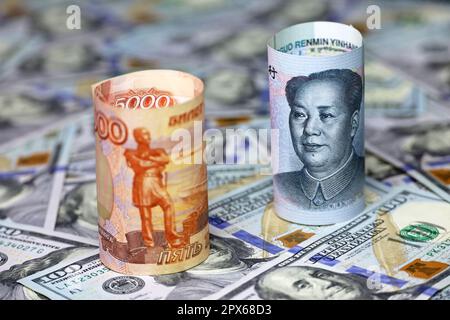 Chinesischer Yuan und russischer Rubel zusammengerollt vor dem Hintergrund von US-Dollar. Wechselkurskonzept, Sanktionen Stockfoto