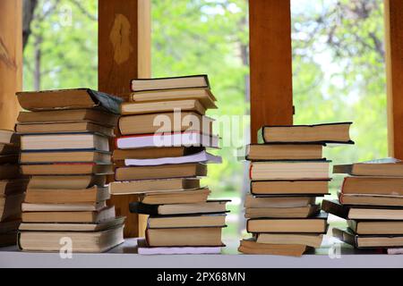 Bücherstapel in einem Park zum Überqueren von Büchern. Hintergrund für Literatur, Buchhandlung, Bibliothek