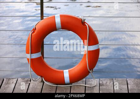 Orangefarbenes Rettungsboot am Strand. Sicherheit auf dem Wasser, Rettungsring auf Holzpier Stockfoto