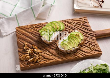 Avocado-Sandwich auf Schwarzbrot mit frisch geschnittenen Avocados von oben gemacht Stockfoto