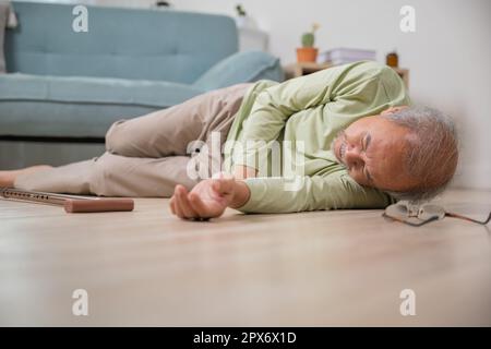 Älterer Senioren Kopfschmerzen, die nach dem Sturz auf dem Boden lagen, Schmerzen und Schmerzen durch Osteoporose, älterer Mann, der allein mit Gehhilfe auf den Boden fällt Stockfoto