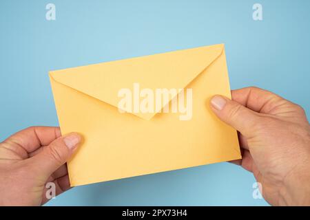 Ein gelber Umschlag in den Händen eines Mannes Stockfoto