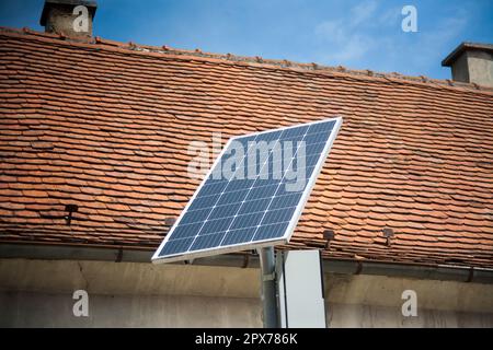 Installierte Solarpaneele auf der Straße. Rotes Dach dahinter. Stockfoto