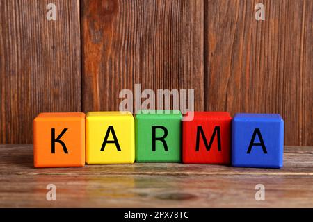 Word Karma aus bunten Würfeln mit Buchstaben auf einem Holztisch Stockfoto