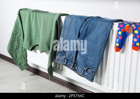 Die Kleidung hing auf dem weißen Heizkörper im Zimmer Stockfoto