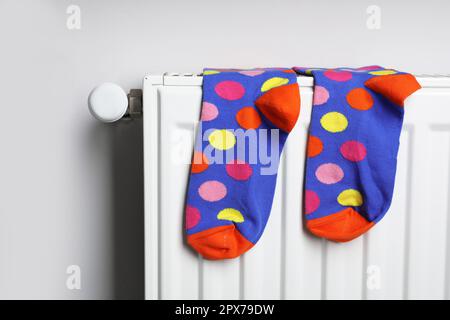 Weißer Radiator mit bunten Socken an hellen Wänden Stockfoto