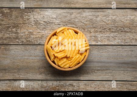 Schüssel mit köstlichen gerippten Kartoffelchips auf einem Holztisch, Draufsicht Stockfoto