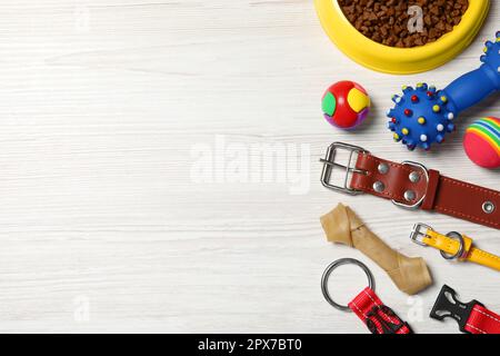 Flach liegend mit Hundehalsband, Spielzeug und Futter auf weißem Holztisch. Platz für Text Stockfoto