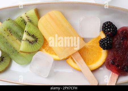 Köstliches Eis am Stiel, Eiswürfel und frisches Obst auf dem Teller, Blick von oben Stockfoto