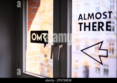 Hamburg, Deutschland. 17. April 2023. „Fast hier“ wird mit einem Pfeil auf einem Fenster neben dem Logo des OME-Unternehmens geschrieben. Wenn das Team des in Hamburg ansässigen Medien- und Digitalunternehmens OMR anruft, fragen viele Entscheidungsträger aus globalen Unternehmen und Prominenten nicht zweimal. Das OMR-Festival bringt auch so viele Menschen in die Stadt, dass es kaum noch Übernachtungsmöglichkeiten gibt. Kredit: Jonas Walzberg/dpa/Alamy Live News Stockfoto