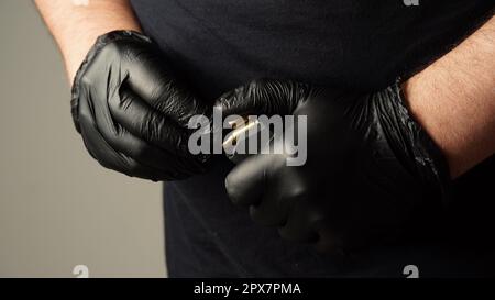 Ein Mann in einem schwarzen T-Shirt lädt den Pistolenhalter mit 9 19 Patronen auf. Die Hände eines Mannes laden ein Pistolenmagazin Stockfoto