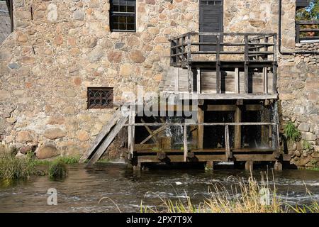 Das Rad der Wassermühle dreht sich unter einem Wasserstrahl. Stockfoto