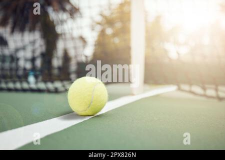 Nahaufnahme eines gelben Tennisballs auf dem Boden, nachdem während eines Spiels auf einem Platz ein Netz geschlagen wurde. Stillleben Ball auf einer Linie während eines Wettkampfsports Stockfoto