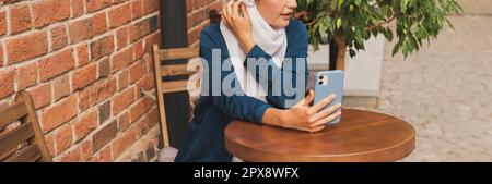 Glückliche muslimische Frau mit Videoanruf auf dem Smartphone in der Stadt. Stockfoto