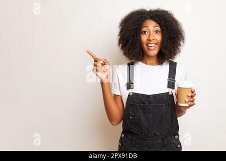 Positive Frau zeigt mit dem Finger auf eine Seite, isoliert auf weißem Hintergrund. Stockfoto