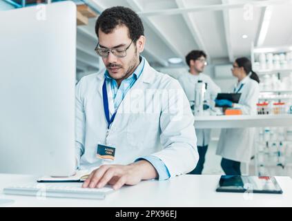 Er recherchiert weiter, bis er zu einer soliden Schlussfolgerung kommt. Ein junger Wissenschaftler, der in einem Labor an einem Computer arbeitet. Stockfoto