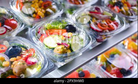 Kunststoffschachteln mit vorverpackten Gemüsesalaten, in Aufmachungen für den Verkauf in einem handelsüblichen Kühlschrank Stockfoto