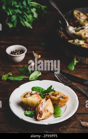 Gebackene Schalen Pasta gefüllt mit Hackfleisch, Spinat und Käse auf weißem Teller Stockfoto