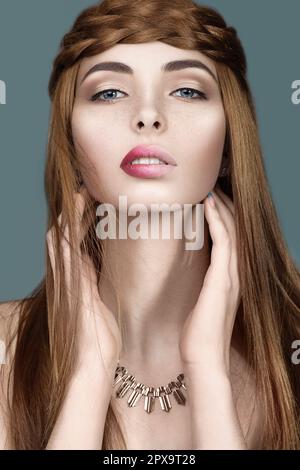 Hübsches rothaariges Mädchen mit Zöpfen und ungewöhnlichen Lippen. Porträt im Studio auf blauem Hintergrund aufgenommen. Stockfoto