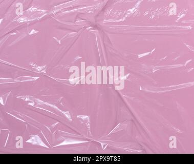 Struktur aus zerknittertem transparentem Polyethylen auf pinkfarbenem Hintergrund, Vollformat. Stockfoto