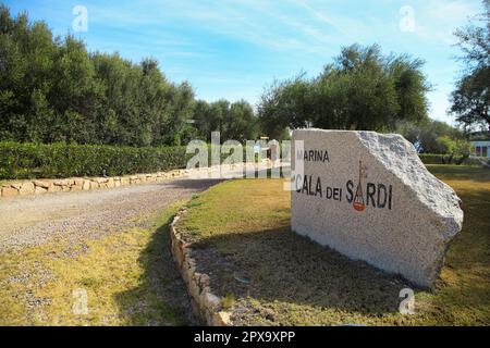 Marina Cala dei Sardi geschrieben in Stein mit Logo, Golf von Cugnana (Golfo di Cugnana) Sardinien April 11 2023 Stockfoto